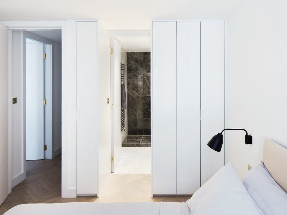 Idée de décoration pour une chambre d'amis minimaliste de taille moyenne avec un mur blanc et parquet clair.