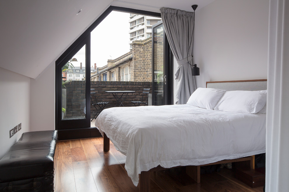 Urban medium tone wood floor bedroom photo in London with white walls