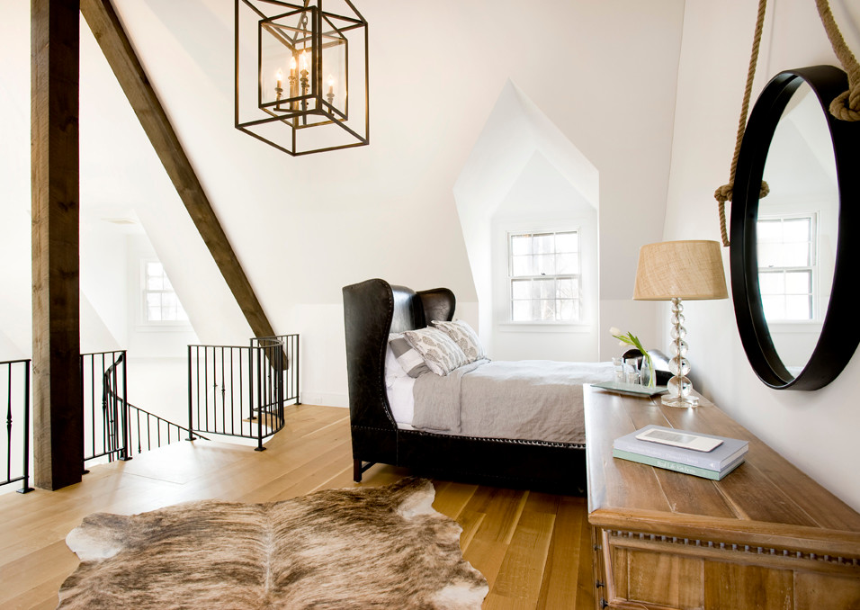 Cette photo montre une chambre mansardée ou avec mezzanine chic avec un mur blanc et un sol en bois brun.
