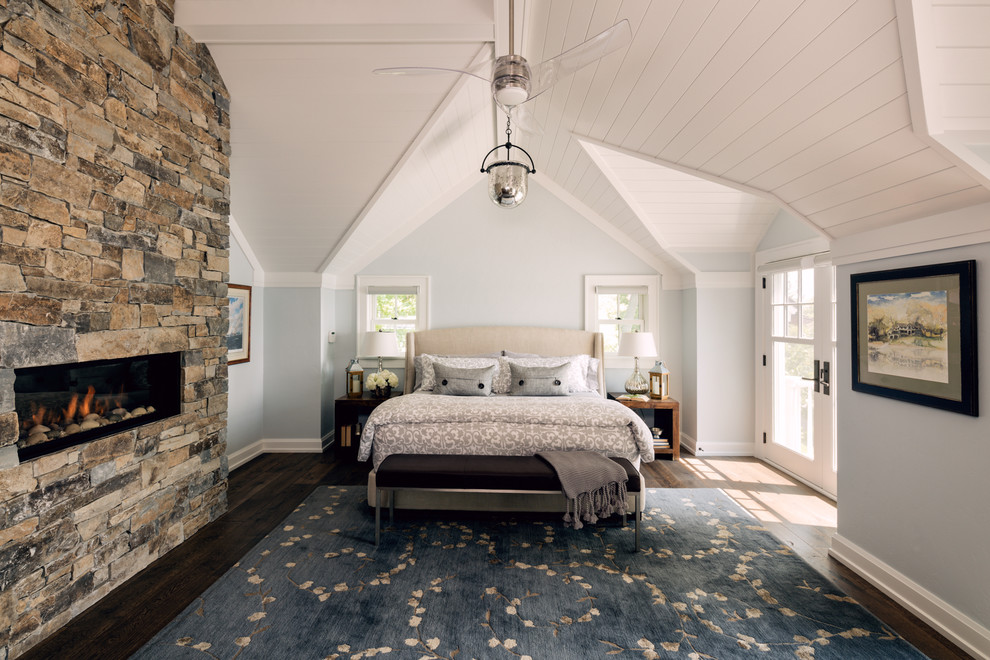 This is an example of a farmhouse master bedroom in Chicago with blue walls, dark hardwood flooring, a ribbon fireplace and a stone fireplace surround.
