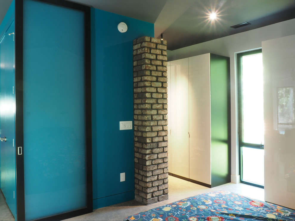 Cette photo montre une petite chambre parentale moderne avec un mur bleu, sol en béton ciré et un sol gris.