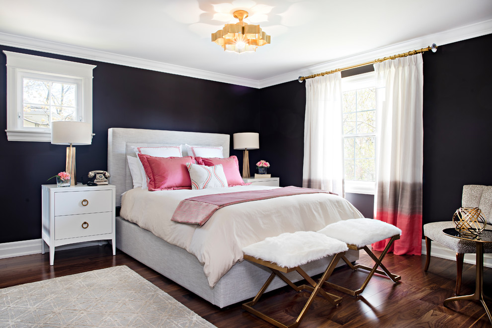 Modelo de dormitorio principal tradicional renovado de tamaño medio con paredes púrpuras, suelo de madera en tonos medios y suelo marrón