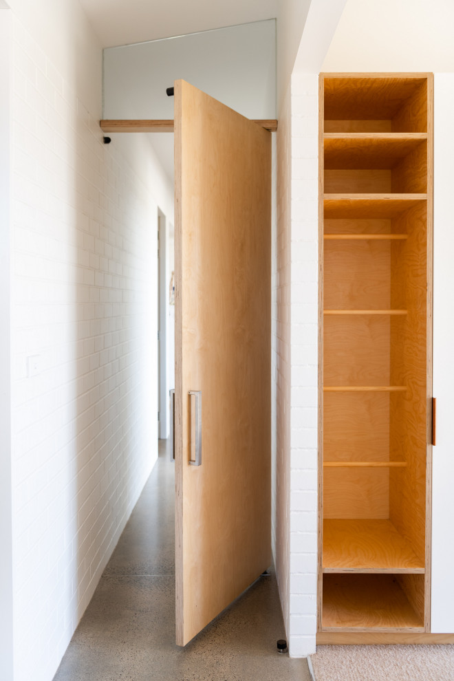 Esempio di una camera da letto minimal di medie dimensioni con pareti bianche, pavimento in cemento, pavimento grigio e pareti in mattoni