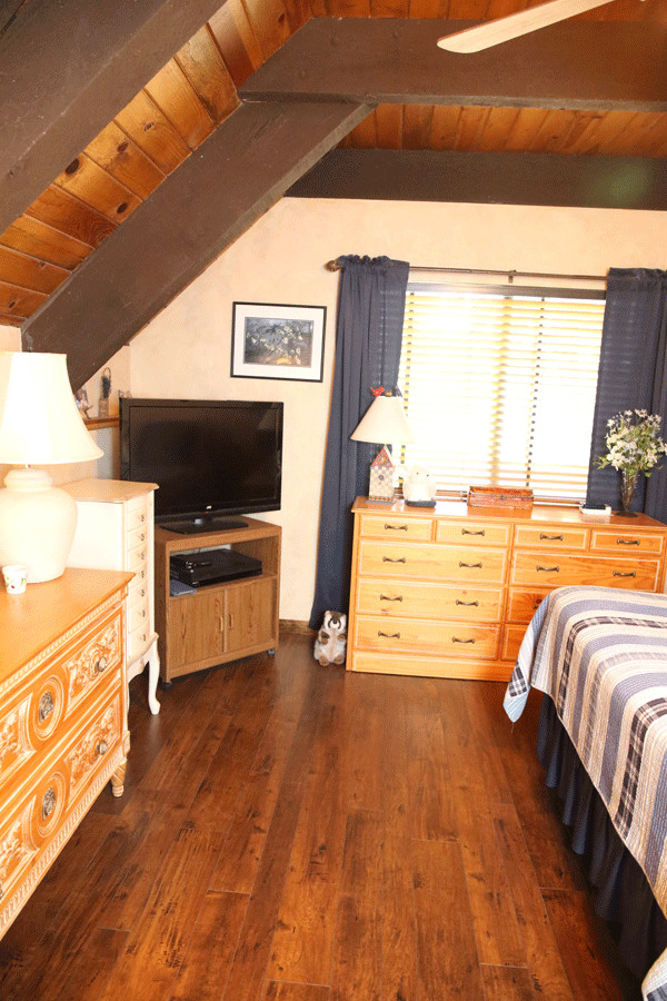 Foto de dormitorio rústico con suelo laminado y suelo marrón