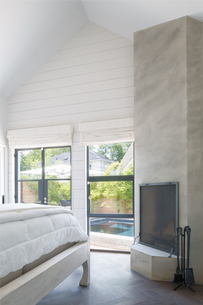 Ejemplo de dormitorio principal moderno de tamaño medio con paredes blancas, suelo de madera en tonos medios, chimenea de esquina, marco de chimenea de yeso y suelo marrón