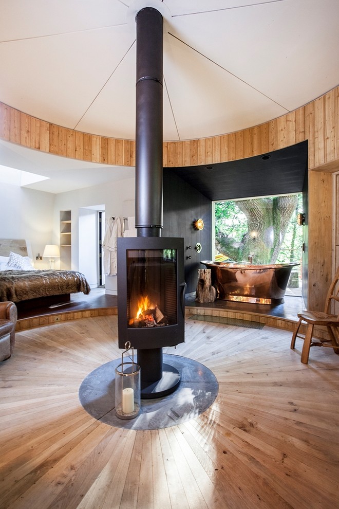 Example of a mid-sized mountain style light wood floor and beige floor bedroom design in Dorset with a wood stove