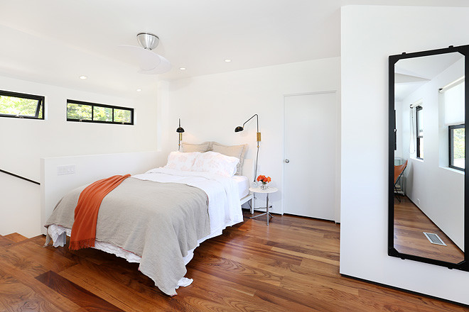 Modelo de dormitorio principal minimalista con paredes blancas y suelo de madera en tonos medios