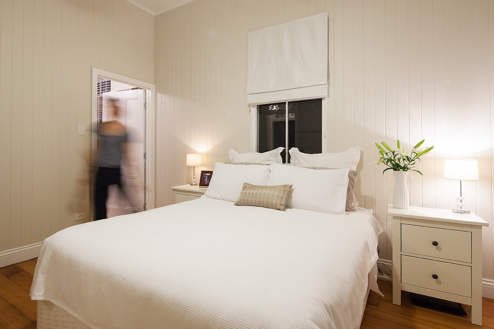 This is an example of a classic guest bedroom in Brisbane with white walls, medium hardwood flooring and no fireplace.