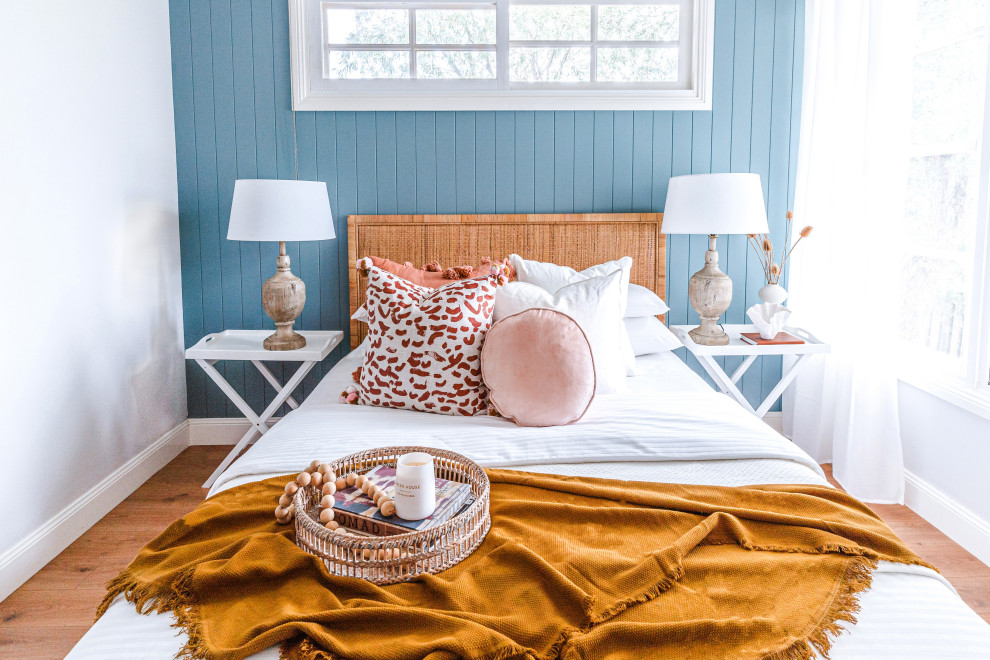 Idée de décoration pour une chambre d'amis bohème avec un mur bleu, parquet clair, un sol marron et du lambris.