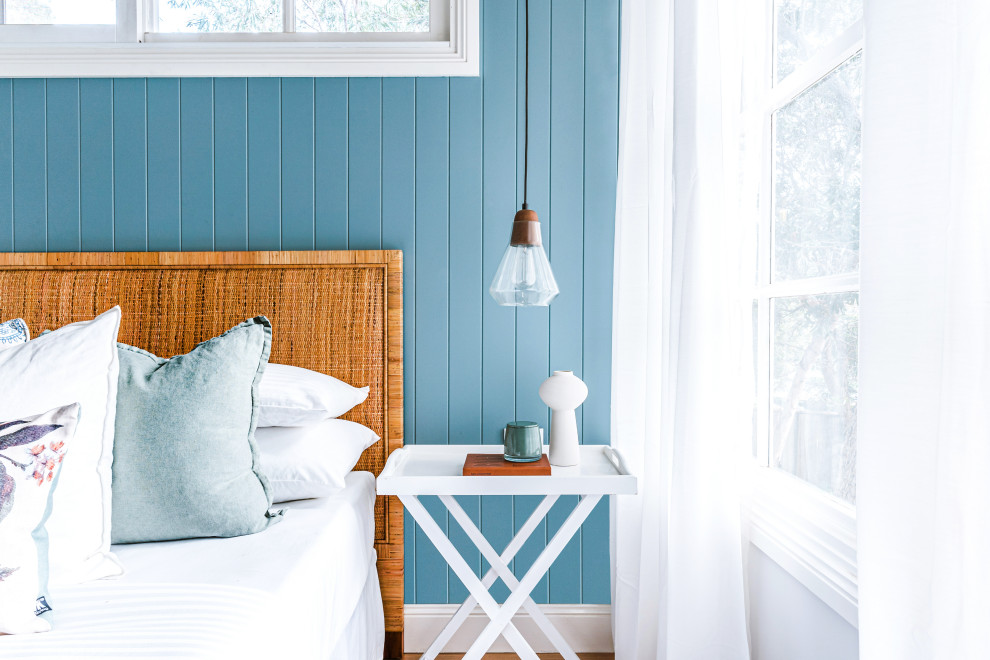 ウーロンゴンにあるビーチスタイルのおしゃれな客用寝室 (青い壁、淡色無垢フローリング、茶色い床、パネル壁) のインテリア