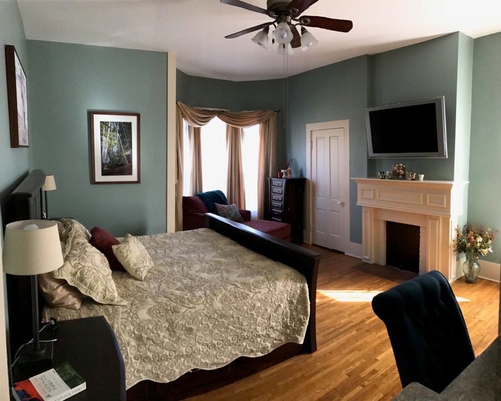 Inspiration for an expansive classic master bedroom in Cleveland with green walls, medium hardwood flooring, a standard fireplace, a wooden fireplace surround and brown floors.