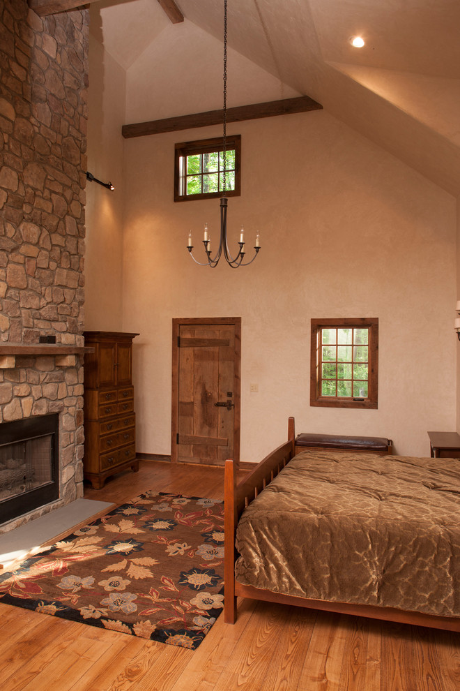 Exemple d'une grande chambre parentale nature avec un mur multicolore, parquet clair, une cheminée standard, un manteau de cheminée en pierre et un sol marron.