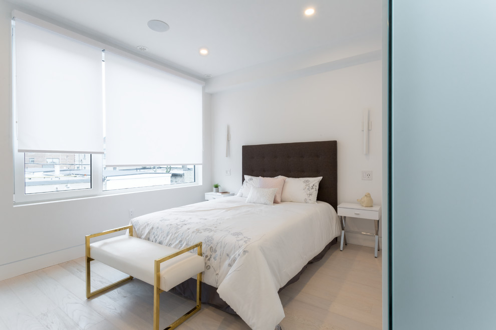 Inspiration for a medium sized modern guest bedroom in Toronto with white walls, light hardwood flooring, a ribbon fireplace, a metal fireplace surround and beige floors.