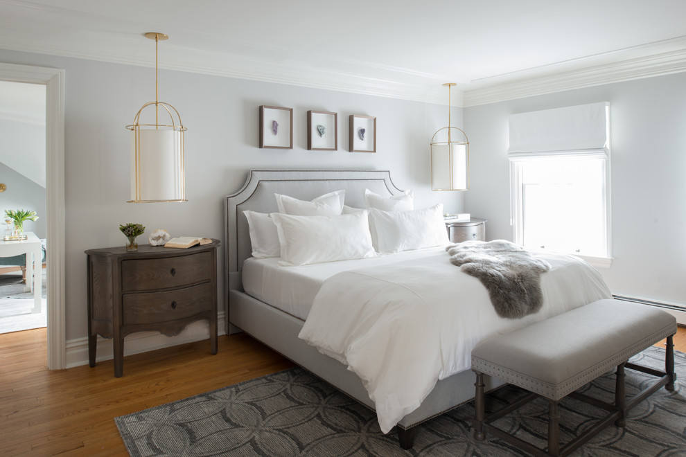 Modelo de dormitorio principal clásico renovado grande con paredes grises, suelo de madera en tonos medios y suelo marrón