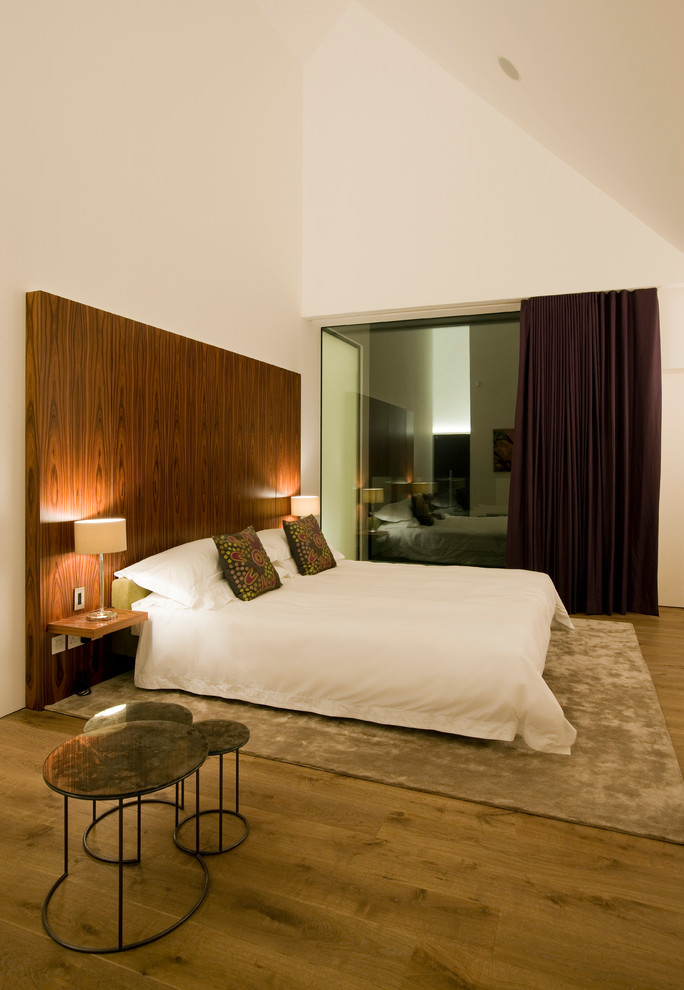 Ispirazione per una camera matrimoniale minimalista di medie dimensioni con pareti bianche, parquet chiaro e pavimento marrone