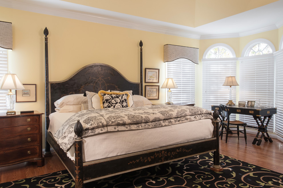 Example of a classic master medium tone wood floor bedroom design in St Louis with yellow walls