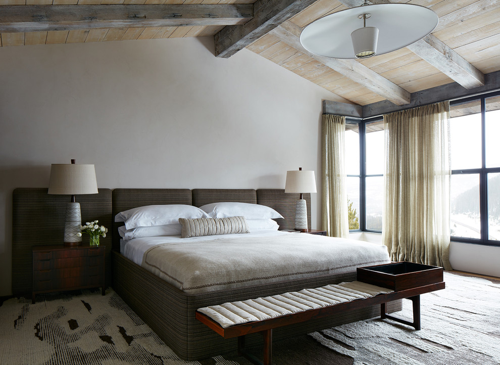 Modelo de dormitorio rural con paredes blancas, suelo de madera en tonos medios y suelo marrón