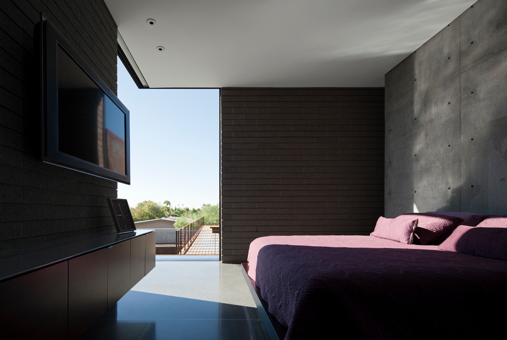 Photo of a modern master bedroom in Phoenix with grey walls and concrete flooring.