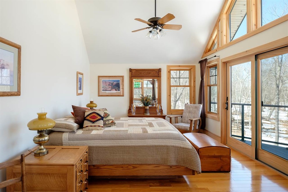 Diseño de dormitorio principal de estilo americano sin chimenea con paredes blancas y suelo de madera en tonos medios