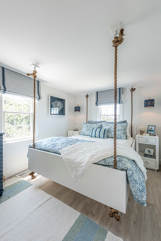 Ejemplo de habitación de invitados costera pequeña sin chimenea con paredes blancas, suelo de madera clara y suelo beige