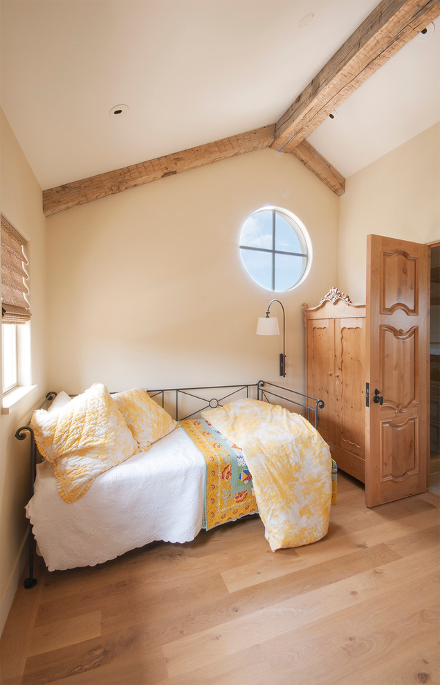 Modelo de habitación de invitados clásica con paredes beige, suelo de madera clara y vigas vistas