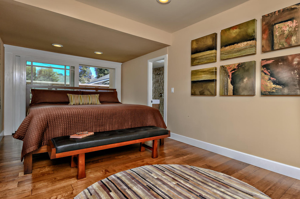 Cette image montre une chambre parentale traditionnelle de taille moyenne avec un mur beige et un sol en bois brun.