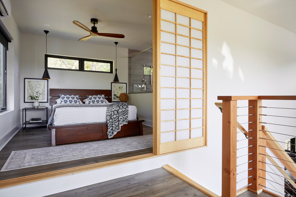 Diseño de dormitorio principal de estilo zen pequeño con paredes blancas, suelo de madera en tonos medios, chimenea de esquina, marco de chimenea de yeso y suelo marrón