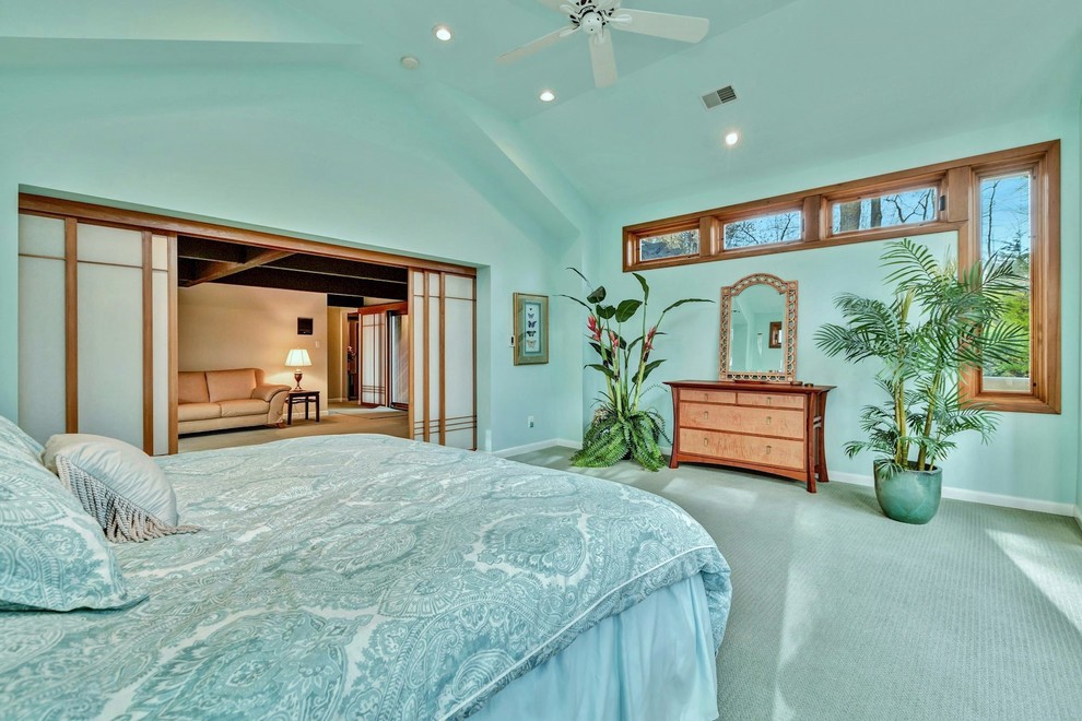 Imagen de habitación de invitados ecléctica extra grande con paredes azules, moqueta, chimenea de esquina, marco de chimenea de piedra y suelo beige