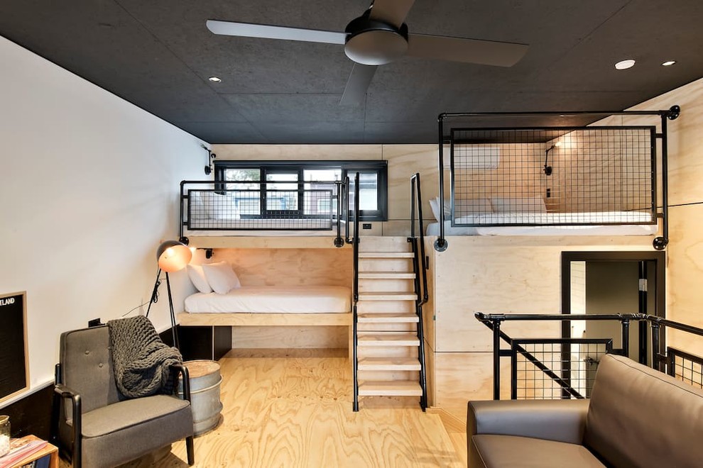 Immagine di una piccola camera da letto stile loft industriale con pavimento in compensato