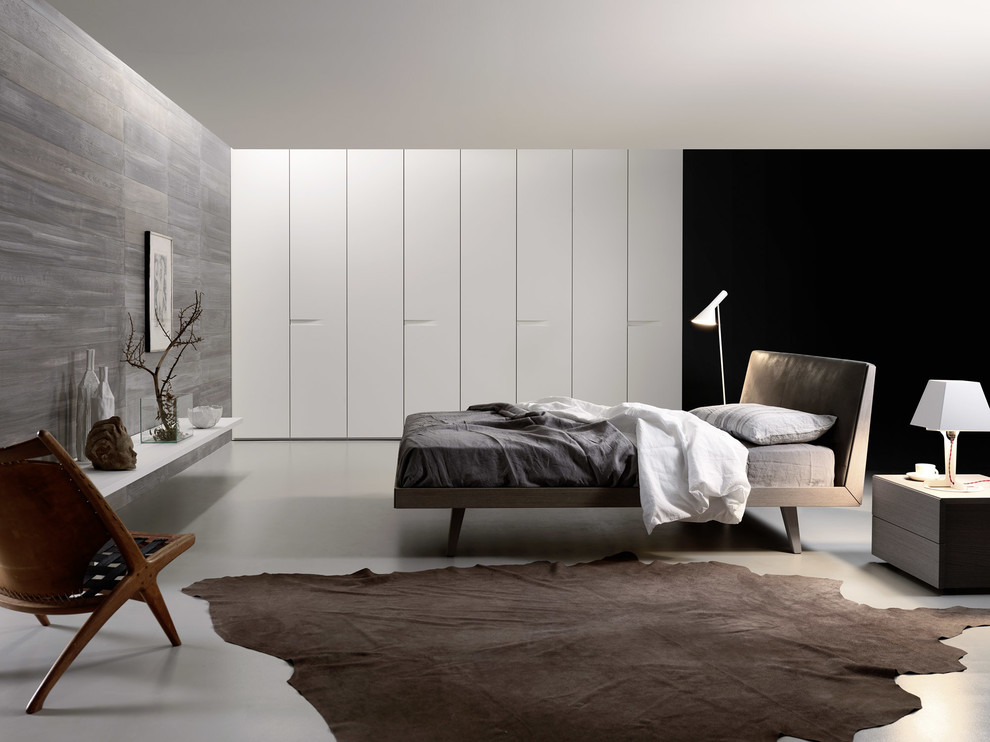 Réalisation d'une grande chambre parentale minimaliste avec un mur blanc et sol en béton ciré.