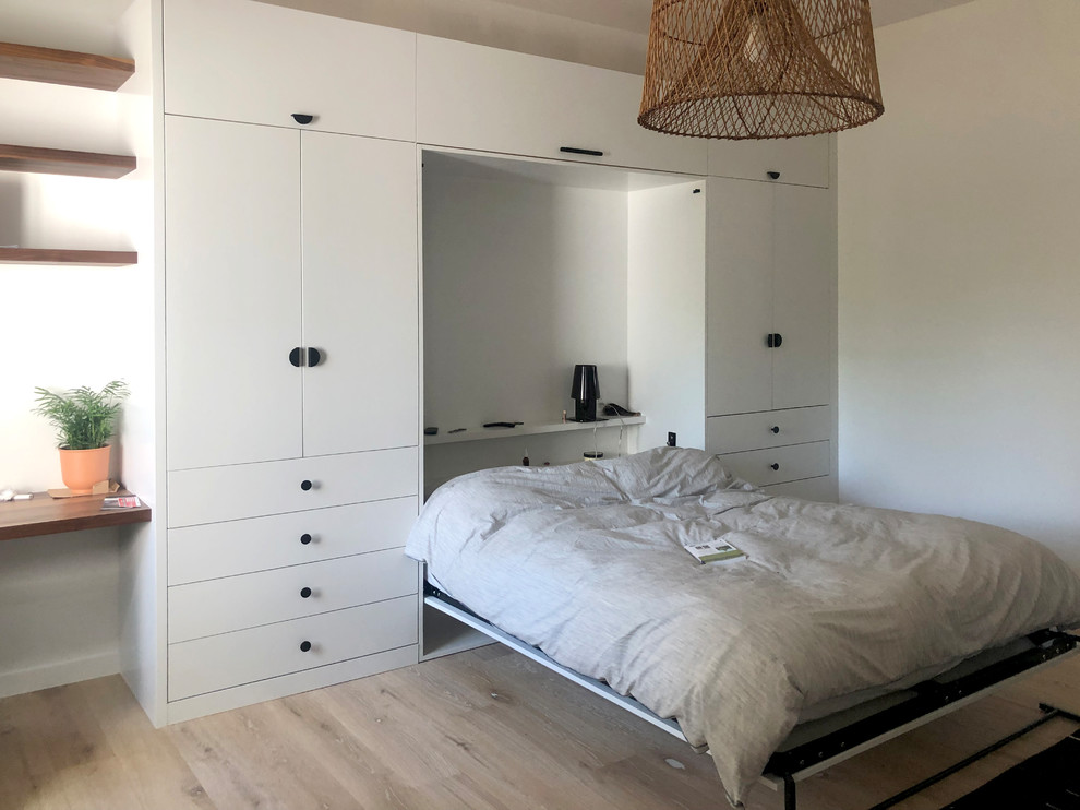 Cette image montre une chambre d'amis minimaliste de taille moyenne avec un mur blanc, parquet clair, aucune cheminée et un sol beige.