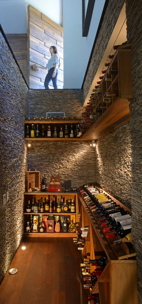 Idées déco pour une cave à vin contemporaine avec un sol en bois brun et un présentoir.