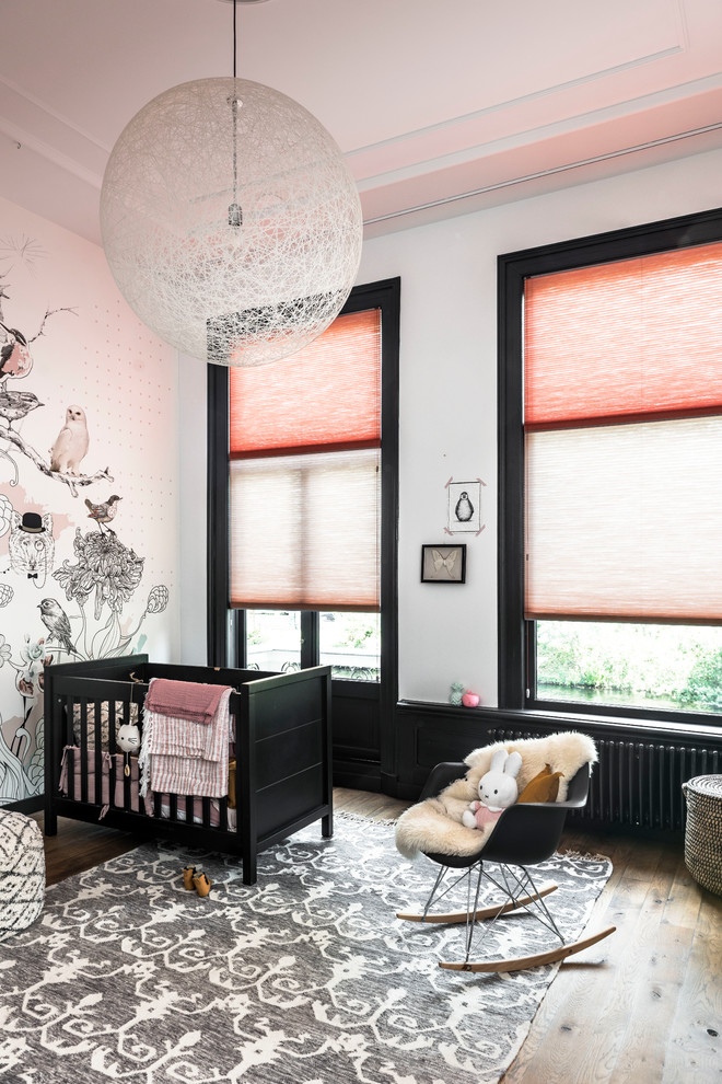 Cette photo montre une chambre d'enfant de 1 à 3 ans scandinave de taille moyenne avec un mur orange et un sol en bois brun.