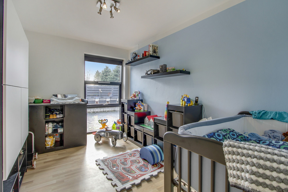 Diseño de dormitorio infantil actual de tamaño medio con suelo de madera clara y paredes multicolor