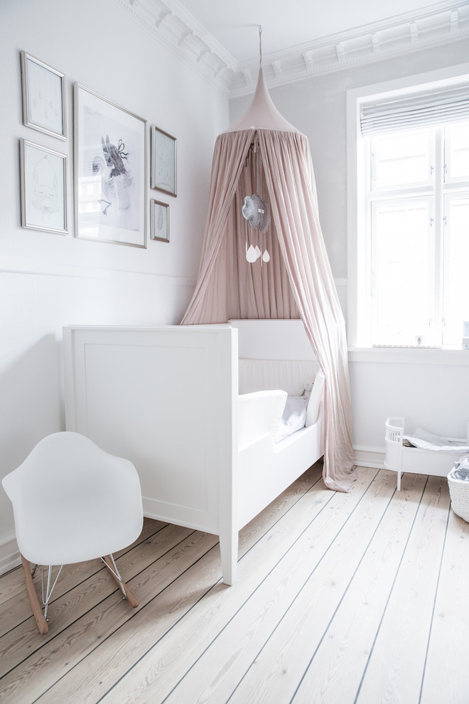 Scandi kids' bedroom for girls in Copenhagen with white walls, light hardwood flooring and beige floors.