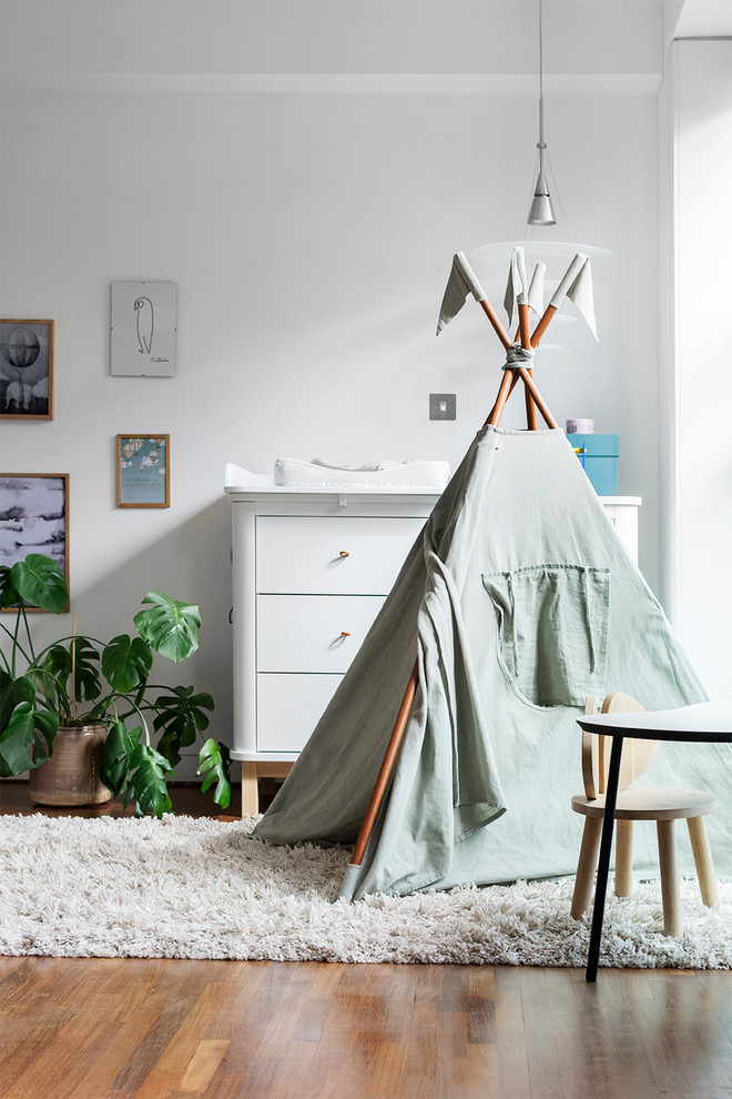 Diseño de dormitorio infantil nórdico con paredes blancas, suelo de madera en tonos medios y suelo marrón