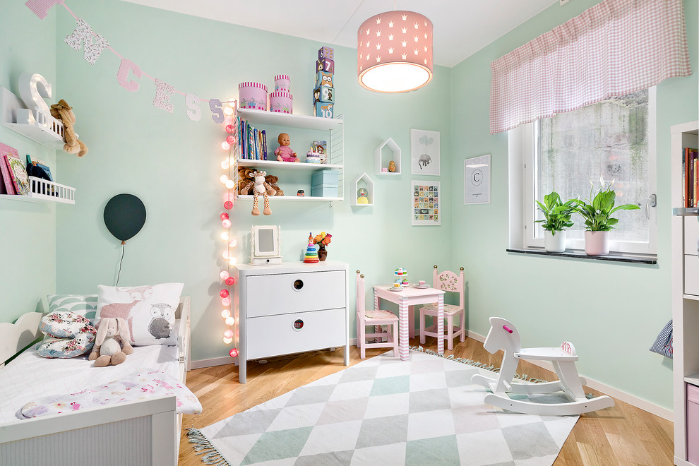 Inspiration for a scandi children’s room for girls in Copenhagen with green walls and medium hardwood flooring.