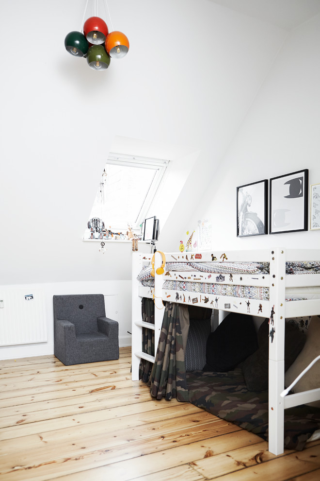 This is an example of a scandi children’s room for boys in Other with white walls and medium hardwood flooring.