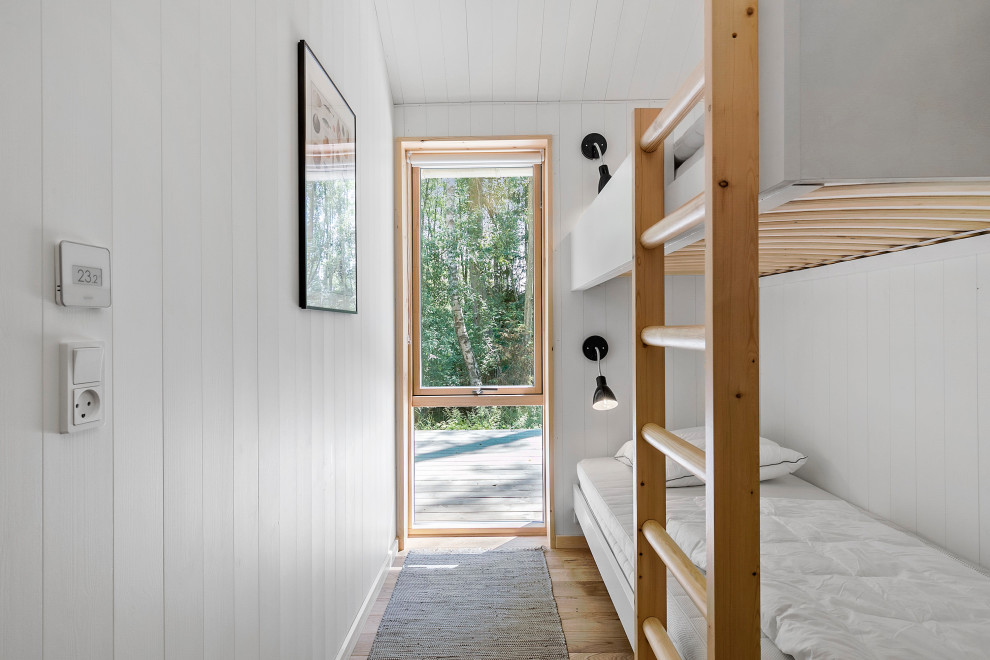 Diseño de dormitorio infantil de 4 a 10 años nórdico con paredes blancas, suelo de madera en tonos medios, suelo marrón y madera