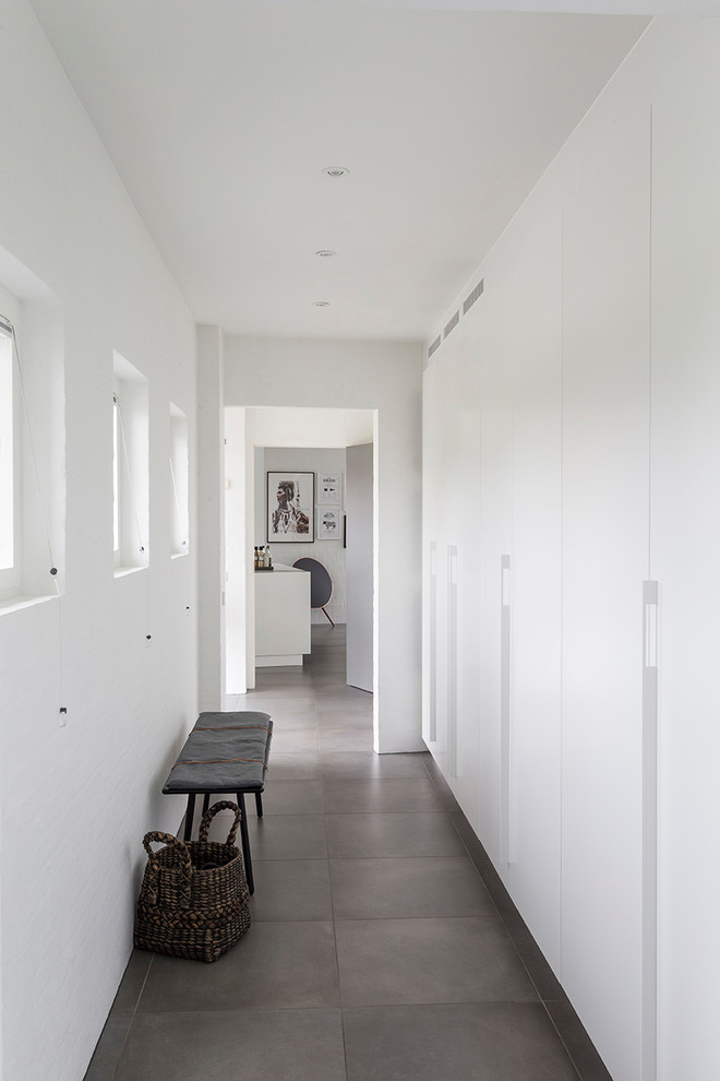 Esempio di una piccola lavanderia design con ante lisce, ante bianche, pareti bianche, pavimento con piastrelle in ceramica, lavatrice e asciugatrice nascoste e pavimento grigio