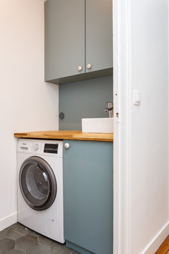 Bild på en liten nordisk bruna parallell brunt liten tvättstuga med garderob, med en nedsänkt diskho, släta luckor, grå skåp, träbänkskiva, vita väggar, klinkergolv i keramik och grått golv