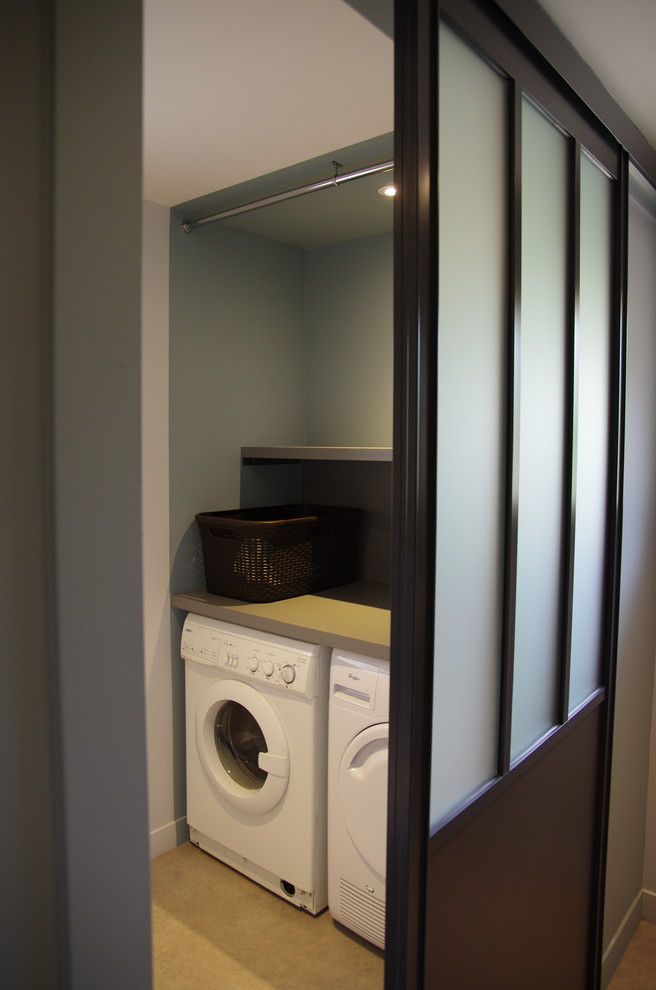Modelo de lavadero multiusos y lineal contemporáneo de tamaño medio con encimera de laminado, paredes azules, suelo vinílico, lavadora y secadora juntas, armarios abiertos, suelo marrón y encimeras beige