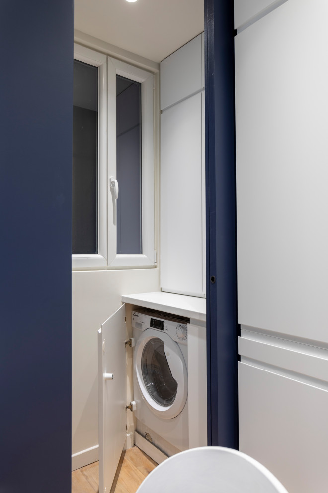 Idee per una piccola lavanderia multiuso contemporanea con ante a filo, ante blu, top in laminato, pareti bianche, pavimento in legno massello medio, lavasciuga, pavimento marrone e top bianco