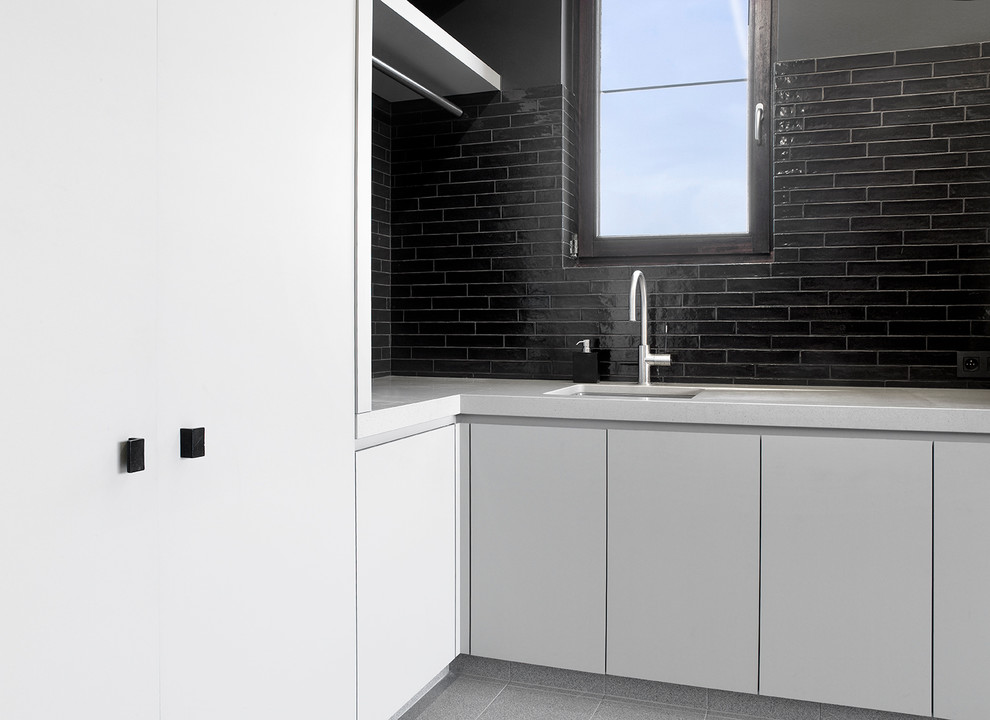 Idee per una lavanderia minimalista con ante grigie, top in quarzite, pareti nere, pavimento con piastrelle in ceramica, lavatrice e asciugatrice a colonna e lavello sottopiano