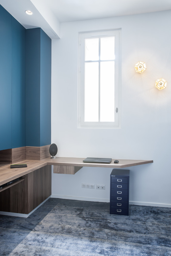 Diseño de despacho contemporáneo de tamaño medio con biblioteca, paredes azules, moqueta, escritorio empotrado y suelo azul