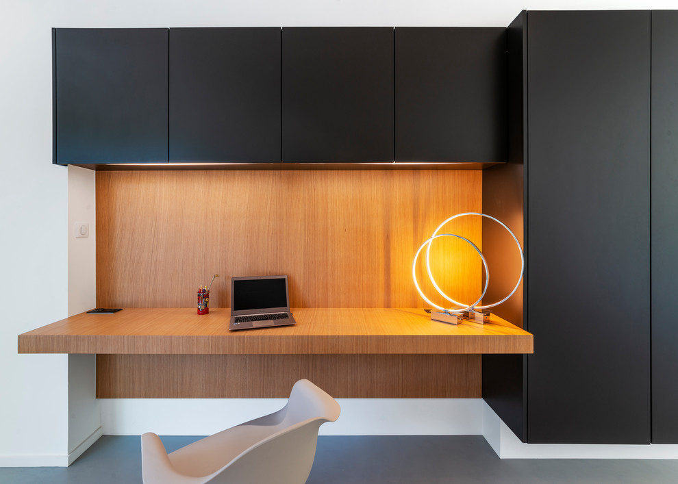 Idee per un ufficio design con scrivania incassata, pavimento in cemento, pavimento grigio e pareti in legno