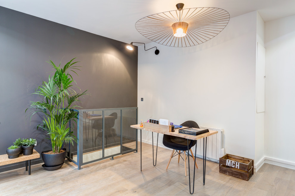 Großes Skandinavisches Arbeitszimmer ohne Kamin mit Arbeitsplatz, weißer Wandfarbe, hellem Holzboden, freistehendem Schreibtisch und beigem Boden in Paris