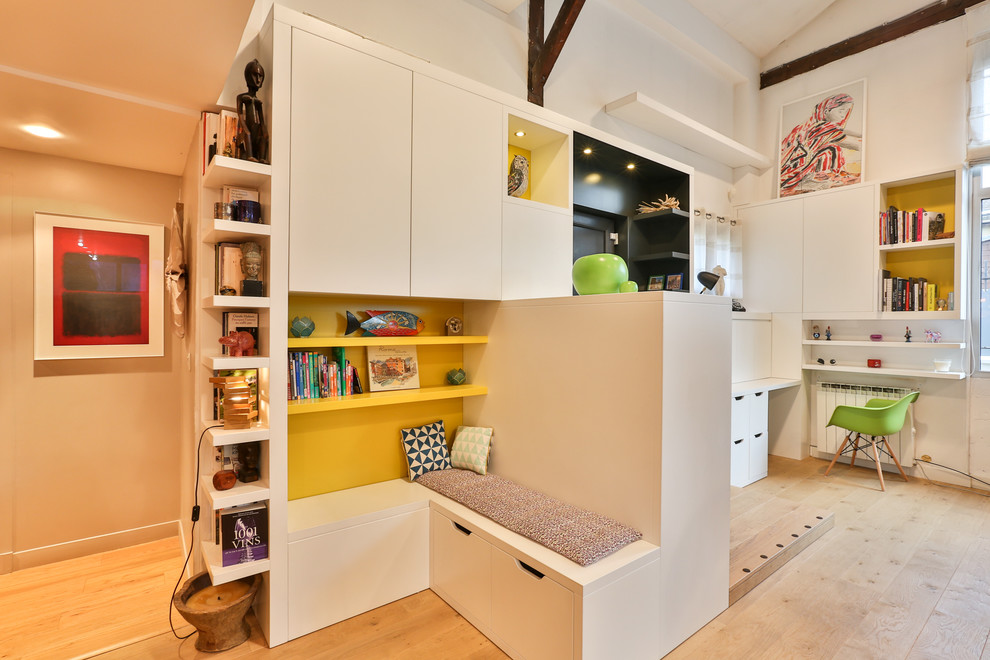 Ejemplo de despacho actual pequeño sin chimenea con paredes amarillas, suelo de madera clara, escritorio empotrado, biblioteca y suelo marrón