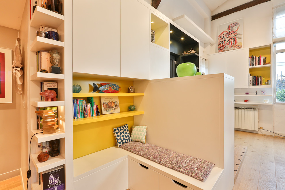 Cette image montre un petit bureau design avec une bibliothèque ou un coin lecture, un mur jaune, parquet clair, aucune cheminée, un bureau intégré et un sol marron.