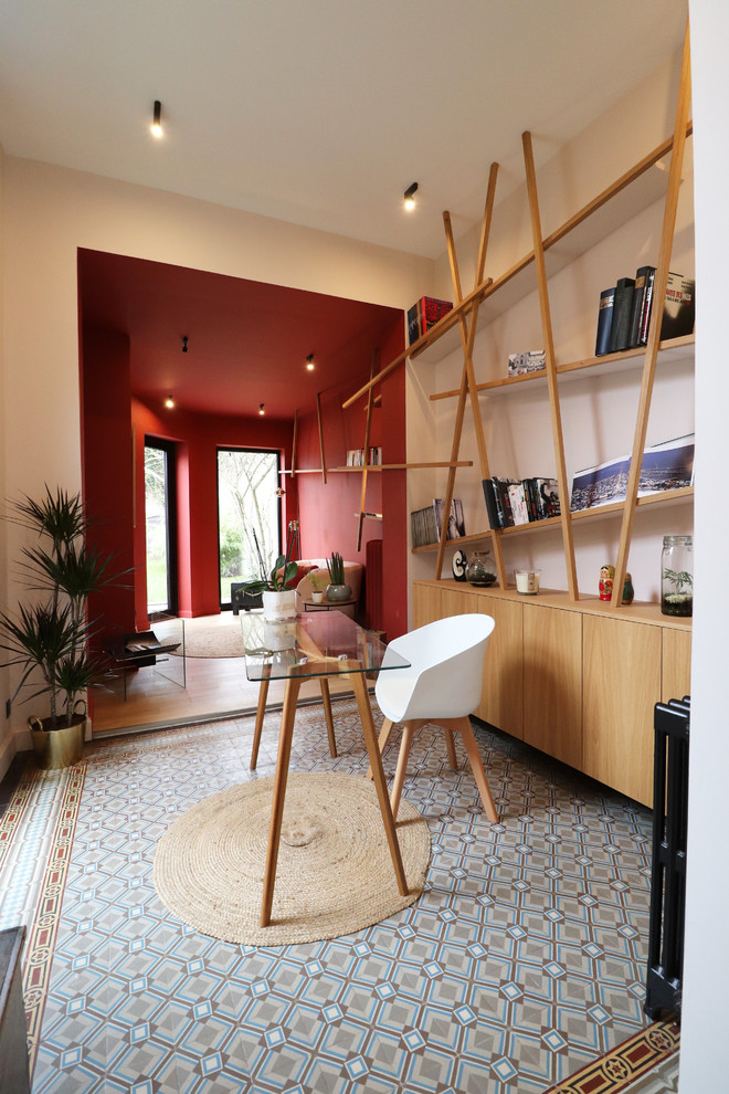 Aménagement d'un bureau contemporain de taille moyenne avec une bibliothèque ou un coin lecture, un mur rose, tomettes au sol, un bureau indépendant et un sol bleu.
